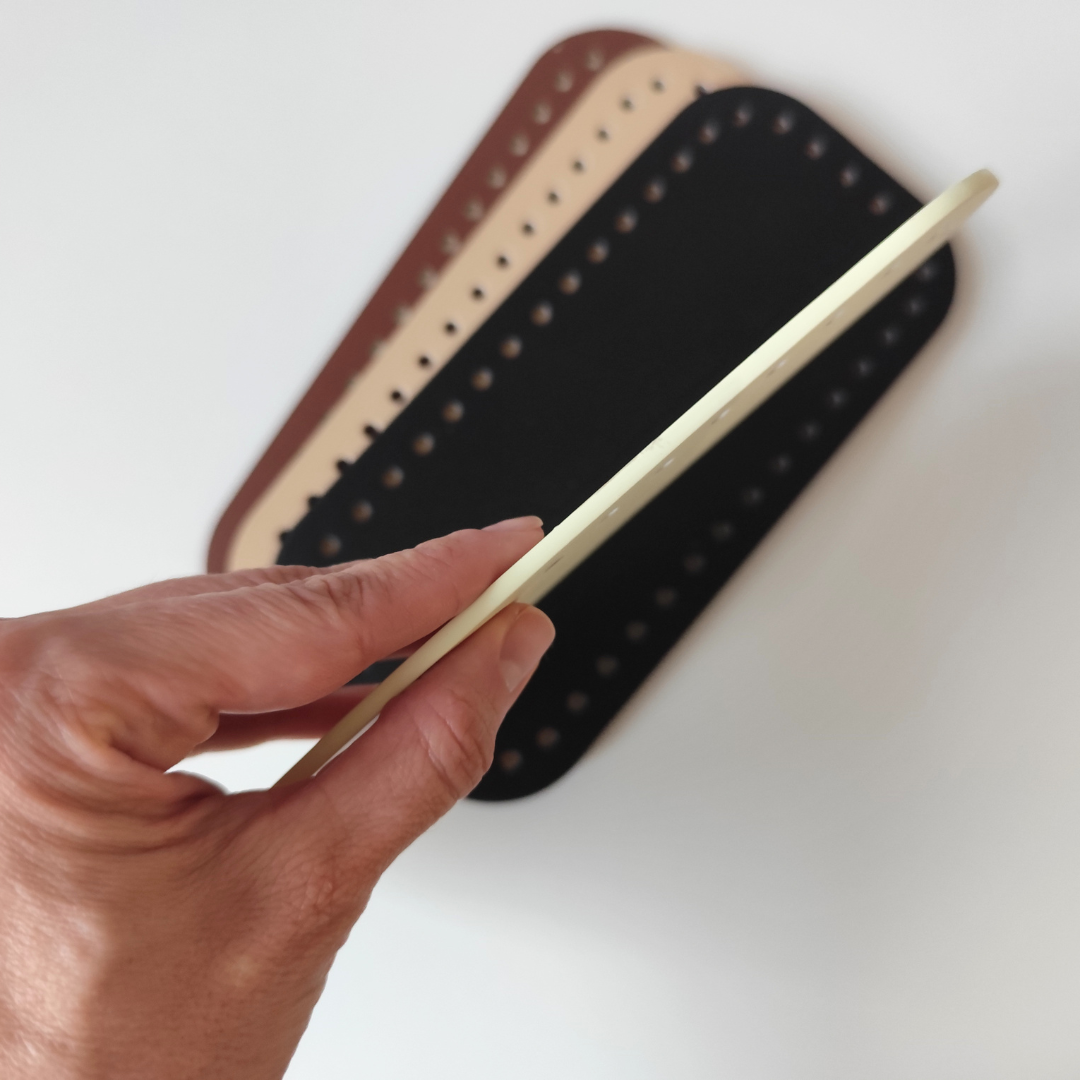 Vegan leather bag base held in hand, showing cream, beige, brown, and black colors
